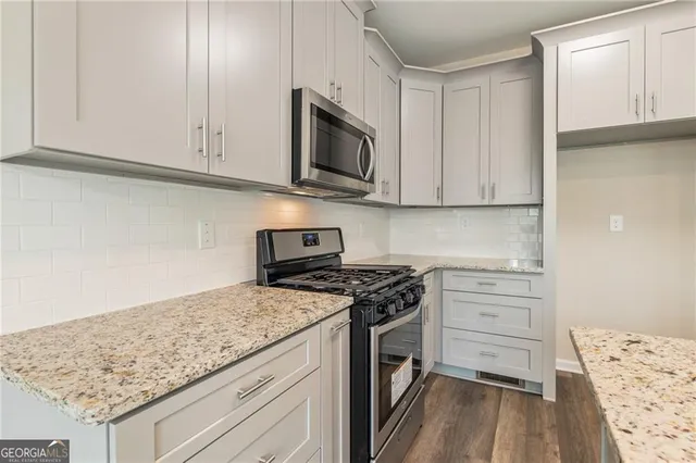 an empty room with wooden floor cabinet and windows