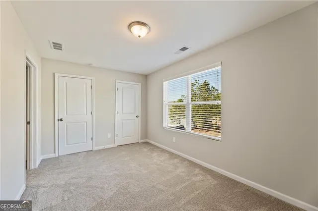 an empty room with chandelier fan and windows