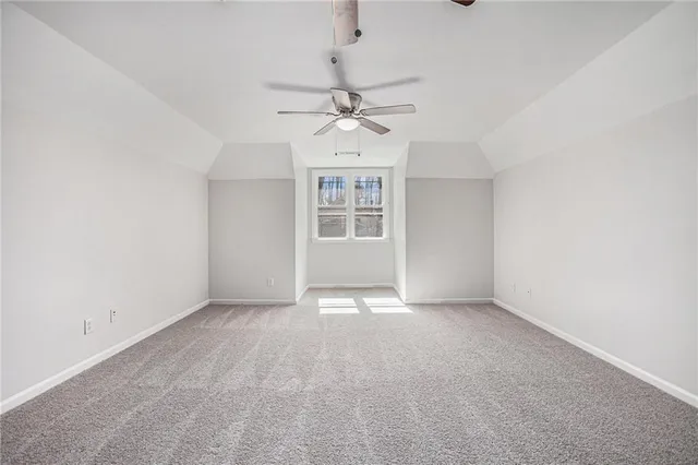 an empty room with chandelier fan and windows