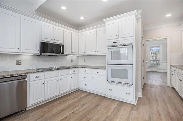 a kitchen with stainless steel appliances white cabinets and wooden floors