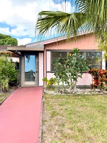 a backyard of a house with table and chairs under an umbrella