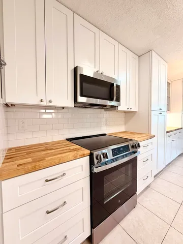 a kitchen with granite countertop white cabinets and stainless steel appliances