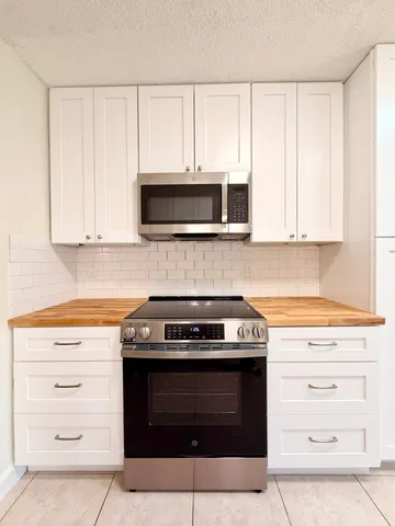 a kitchen with granite countertop a stove and a microwave