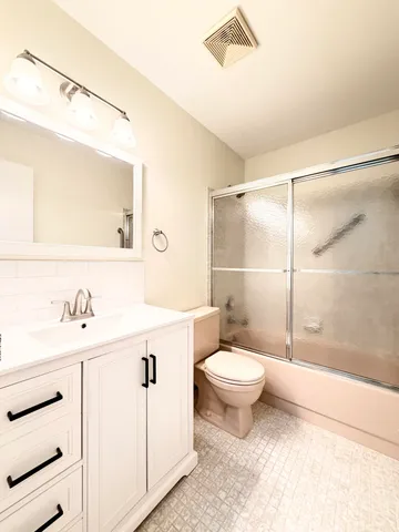 a bathroom with a toilet sink vanity shower and mirror