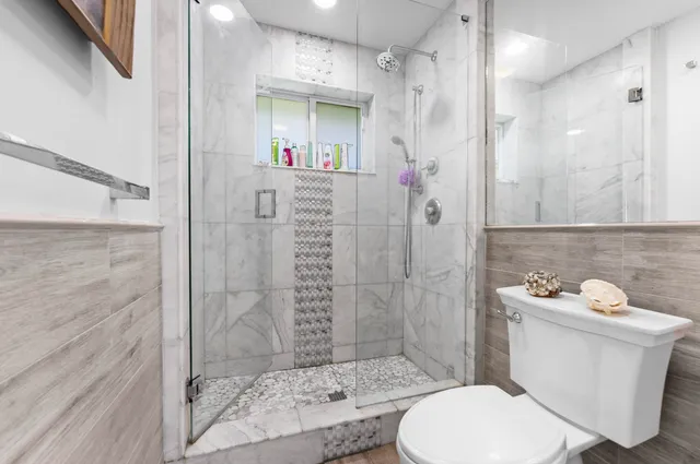 a bathroom with a sink a toilet a shower and a mirror