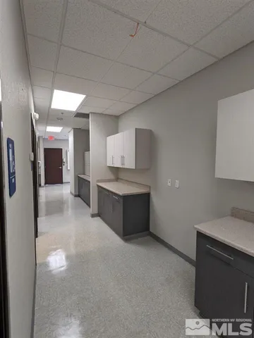 a large white kitchen with a sink and dishwasher a stove top oven with wooden floor