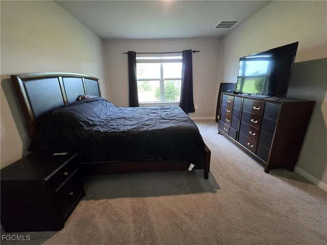 a bedroom with a bed and a flat tv screen on a dresser