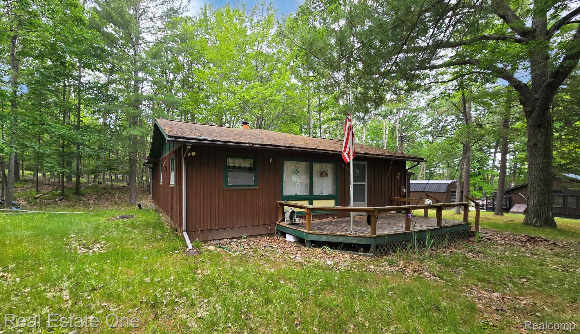 4233 Pheasant Road Lincoln, MI 48742 - Photo 3 of 19 Wood-paneled siding exterior with a brown roof and a front deck