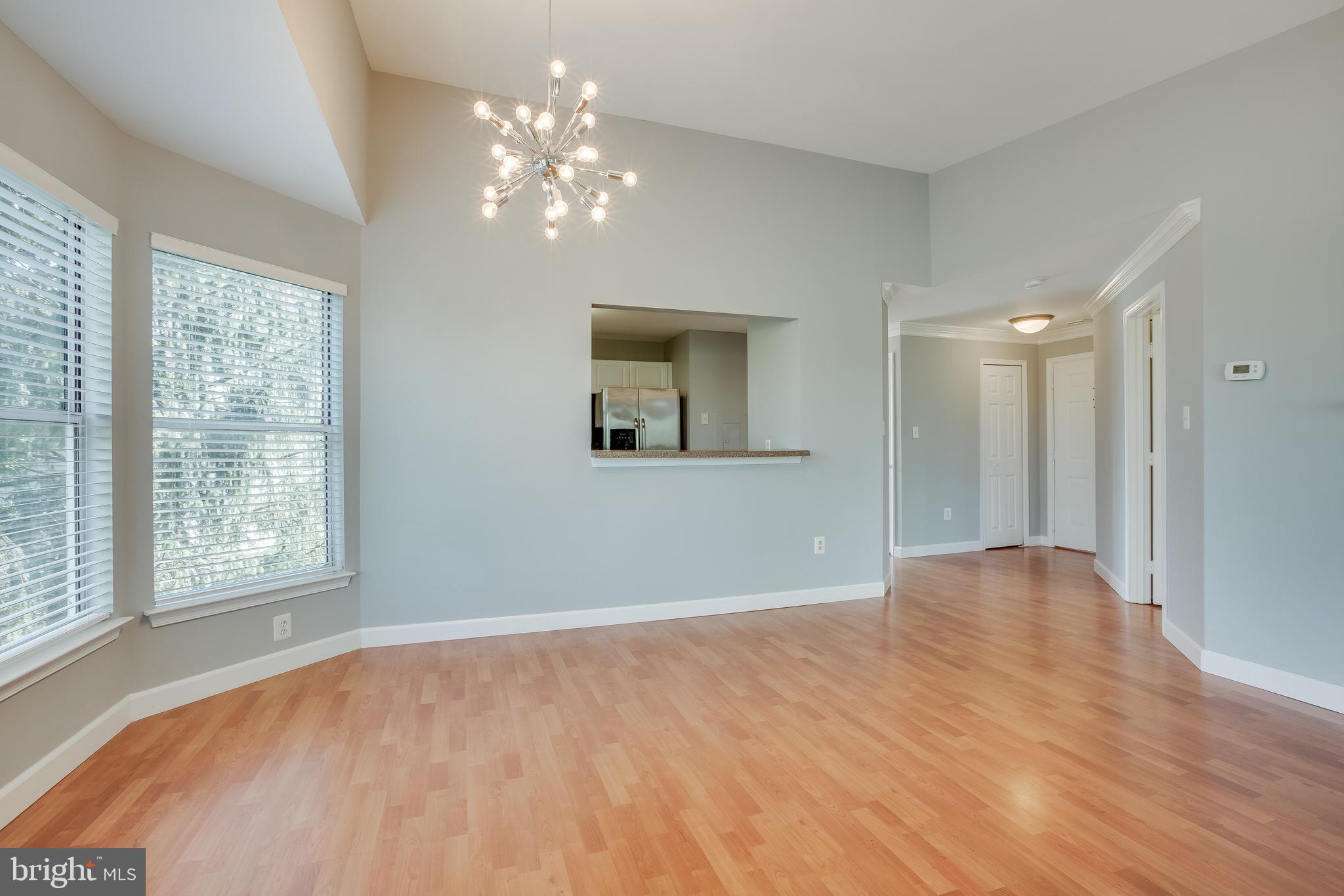 20575 Snowshoe Square, Unit 302 Ashburn, VA 20147 - Photo 3 of 32 a view of an empty room with a chandelier fan and a window
