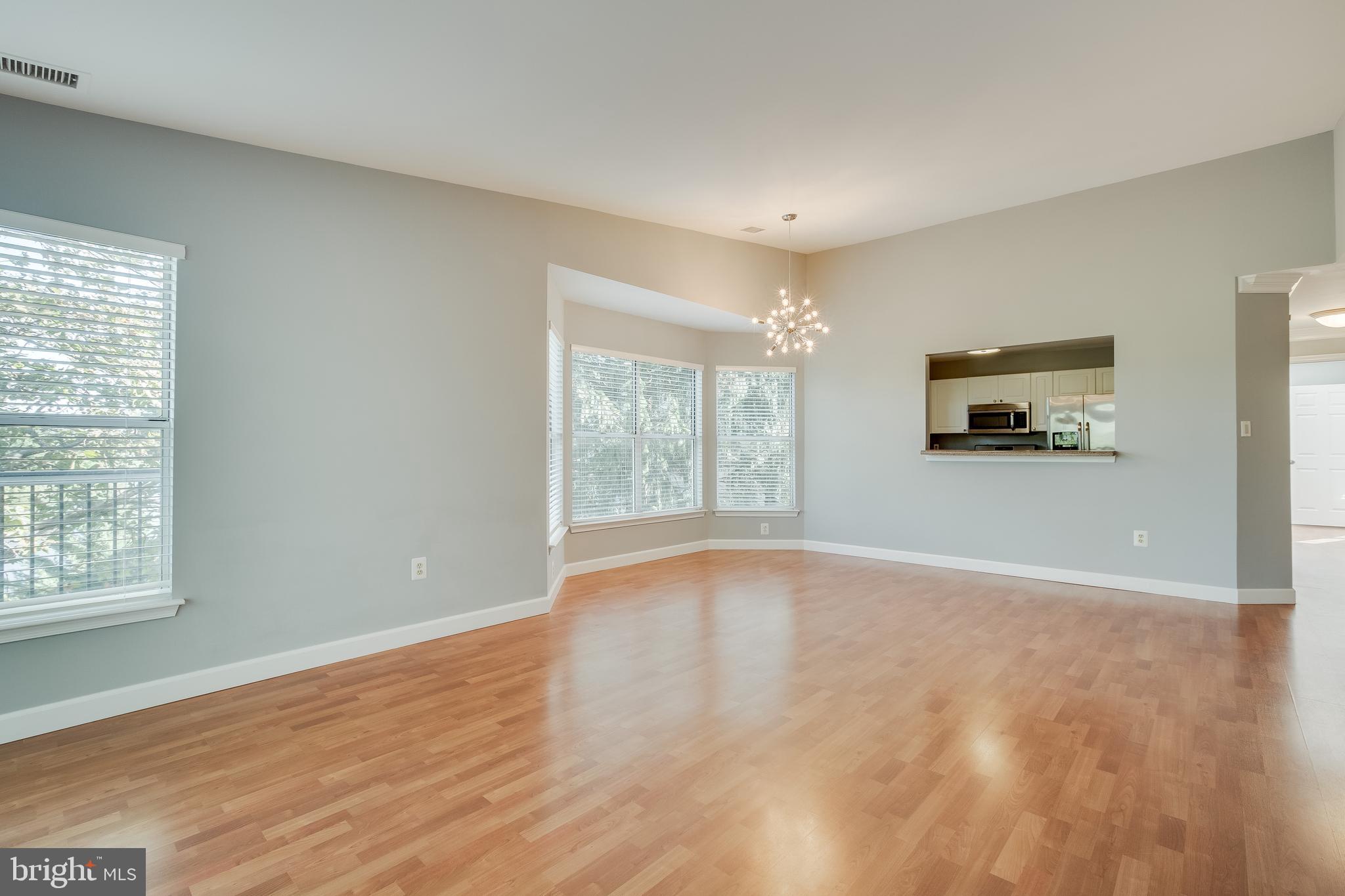 20575 Snowshoe Square, Unit 302 Ashburn, VA 20147 - Photo 25 of 32 an empty room with wooden floor and windows