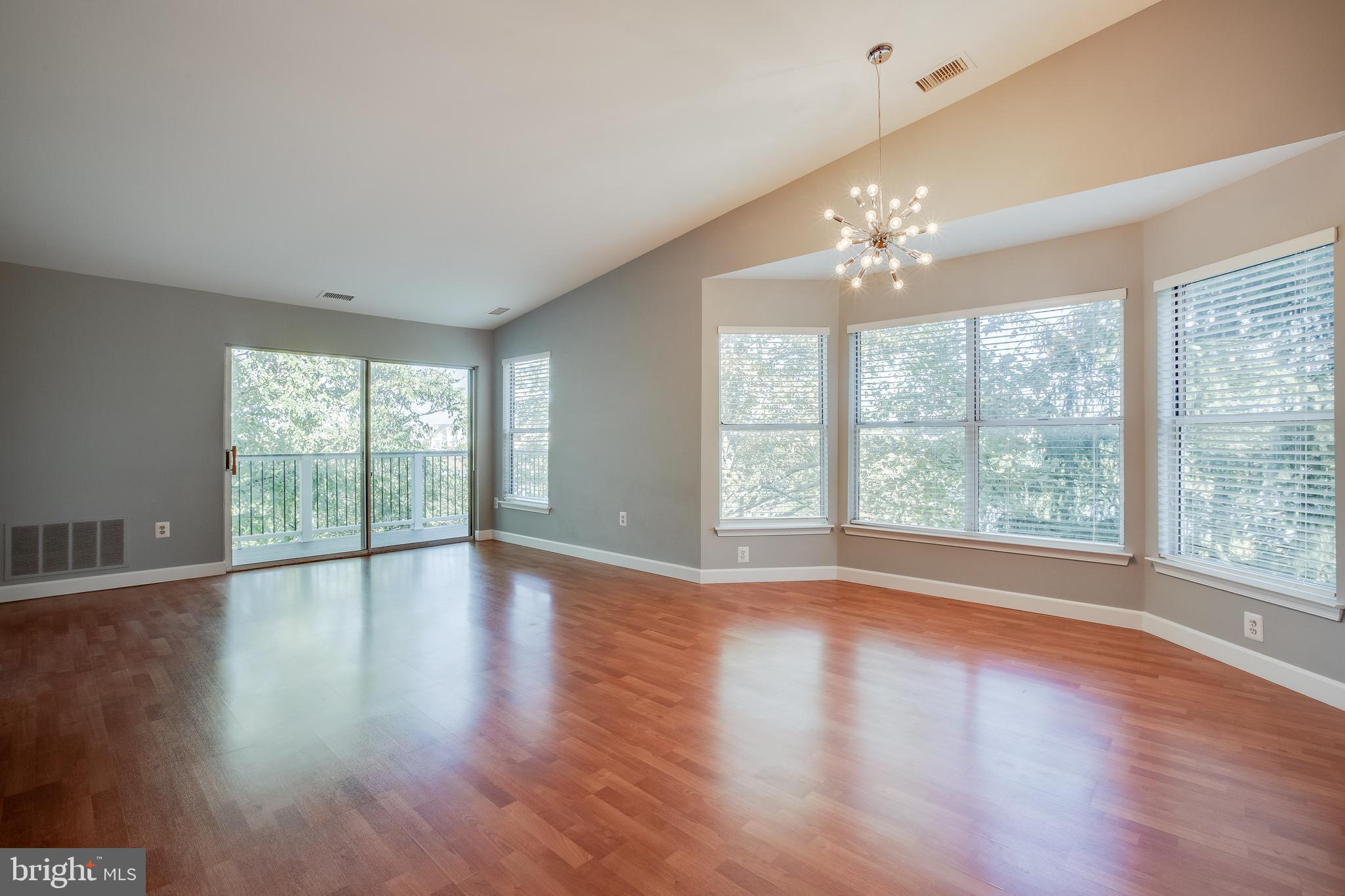 20575 Snowshoe Square, Unit 302 Ashburn, VA 20147 - Photo 4 of 32 a view of an empty room with wooden floor and a window