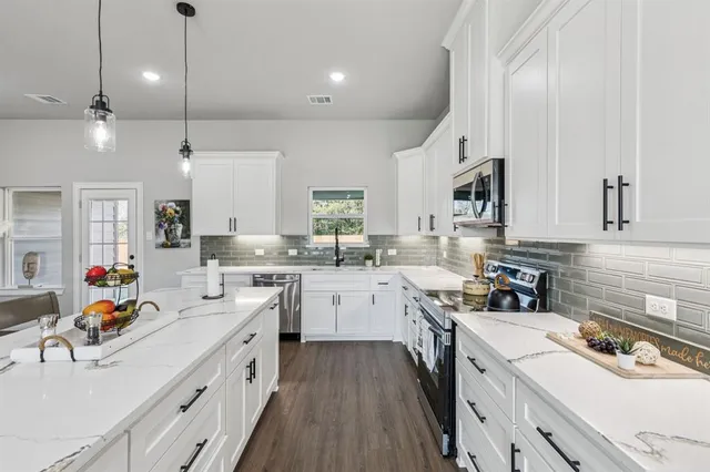 a kitchen with stainless steel appliances kitchen island granite countertop a table chairs and a refrigerator