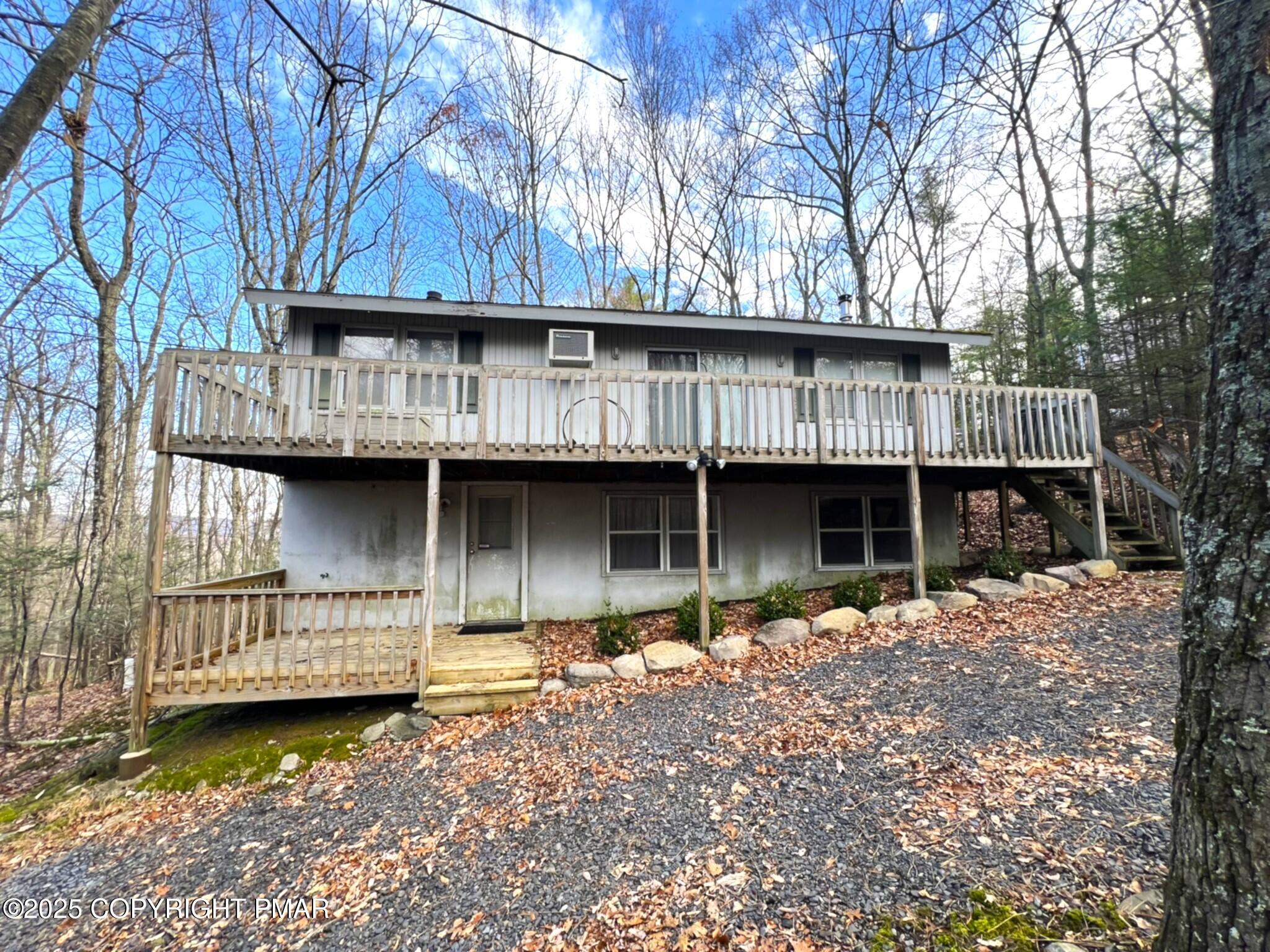 a backyard of a house with wooden deck and a large tree