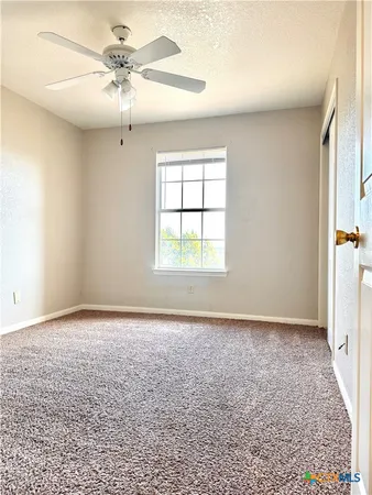 an empty room with a window and a fan