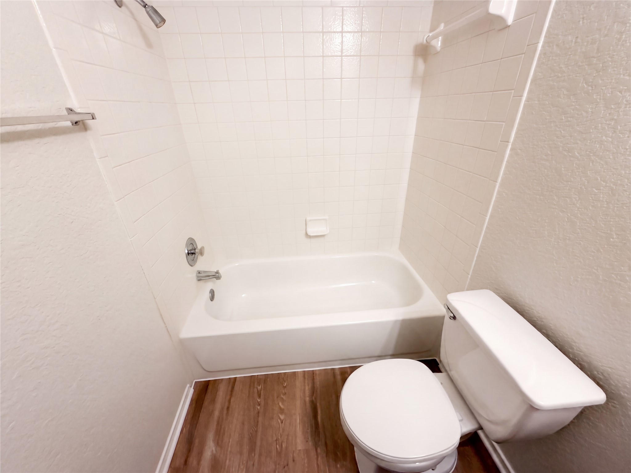 172 Prairie Springs Loop Georgetown, TX 78626 - Photo 16 of 32 Tiled walls surround a classic bathtub complemented by wood-look flooring.