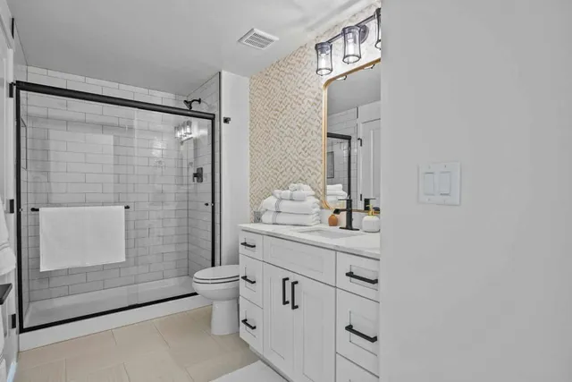 a bathroom with a granite countertop sink a toilet and shower