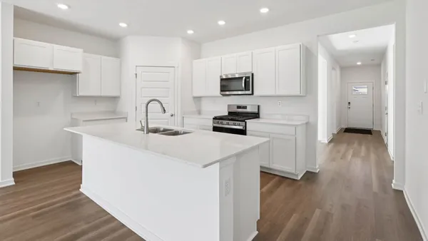 a kitchen with stainless steel appliances granite countertop a sink a stove a refrigerator and cabinets with wooden floor