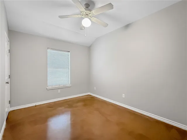 an empty room with a ceiling fan and carpet
