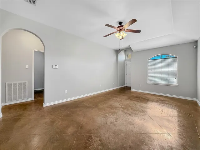 an empty room with windows and fan
