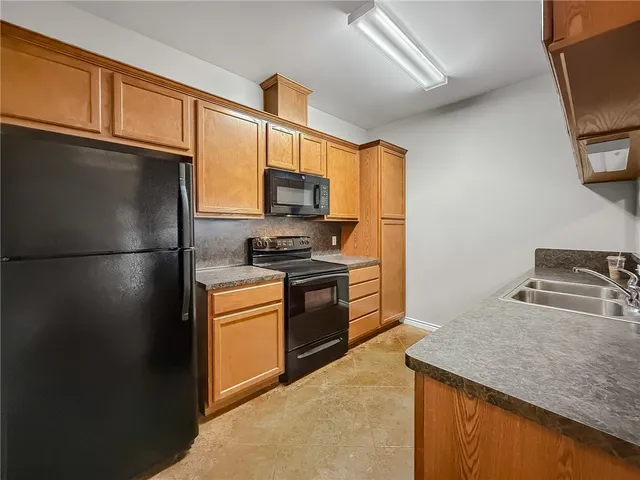 a kitchen with stainless steel appliances granite countertop a refrigerator a stove a sink and a microwave