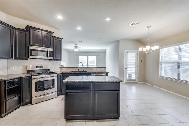 a kitchen with kitchen island granite countertop a stove sink and microwave