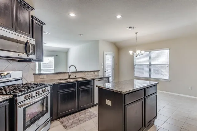 a kitchen with stainless steel appliances granite countertop a sink stove and cabinets