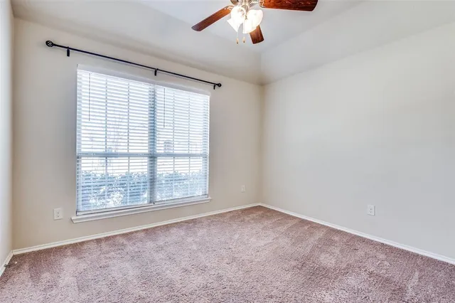an empty room with a window and a ceiling fan