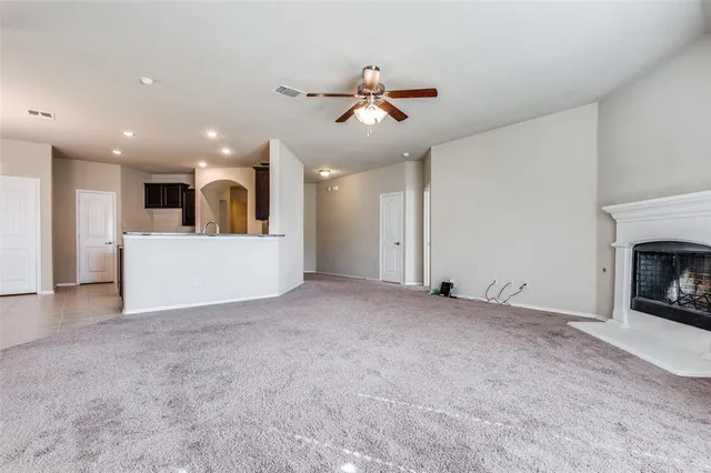 a view of a livingroom with a fireplace a ceiling fan and windows