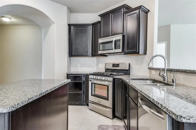 a kitchen with stainless steel appliances granite countertop a sink stove and refrigerator