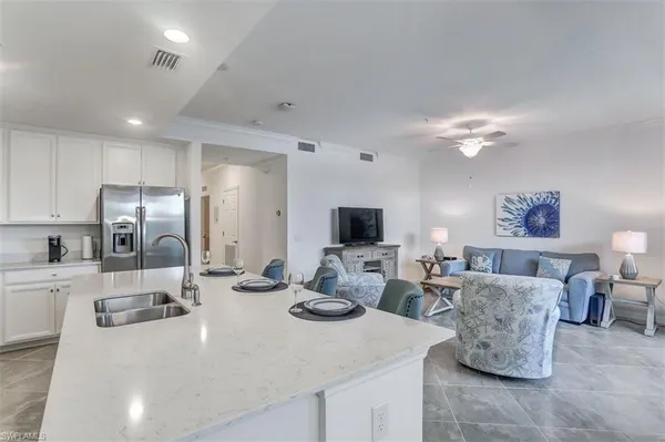 a kitchen with stainless steel appliances kitchen island granite countertop a sink and a refrigerator