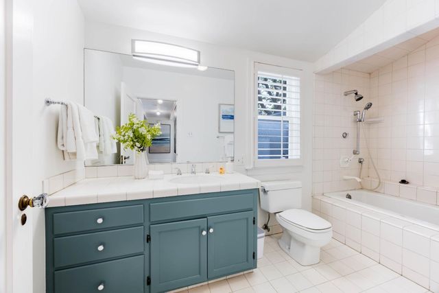 a bathroom with a granite countertop sink mirror vanity bathtub and a toilet