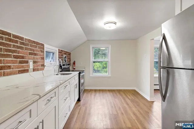 a large kitchen with a lot of white cabinets and wooden floor