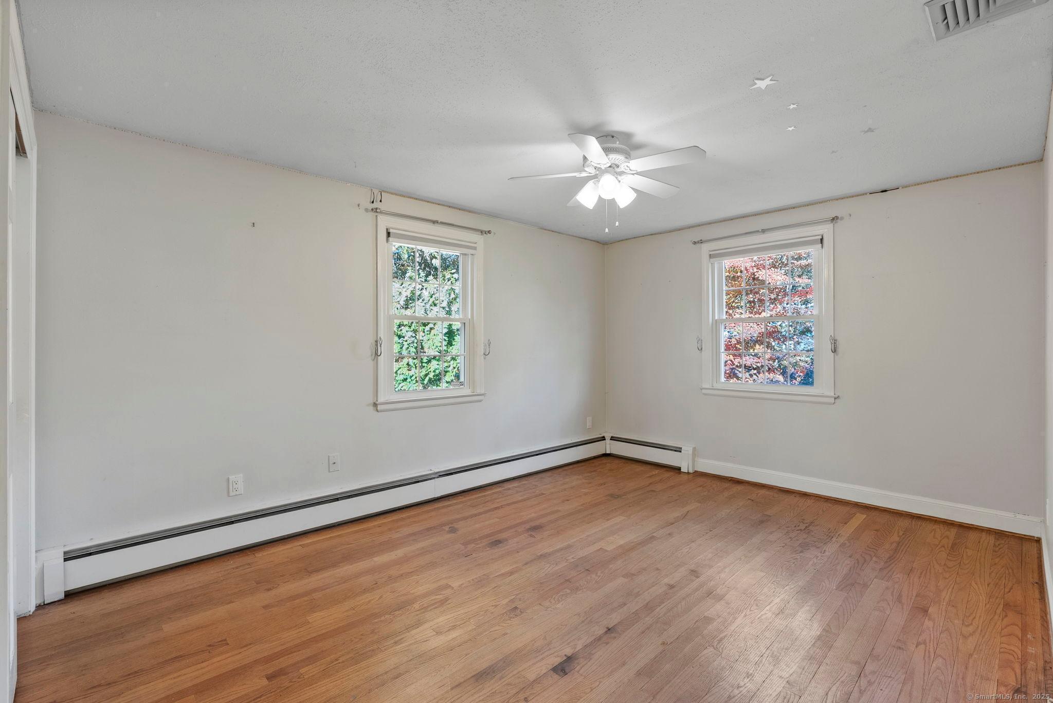 23 Wagon Road Glastonbury, CT 06033 - Photo 24 of 40 an empty room with wooden floor chandelier fan and windows