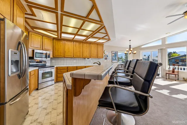 a view of kitchen with stainless steel appliances wooden cabinets dining table and chairs