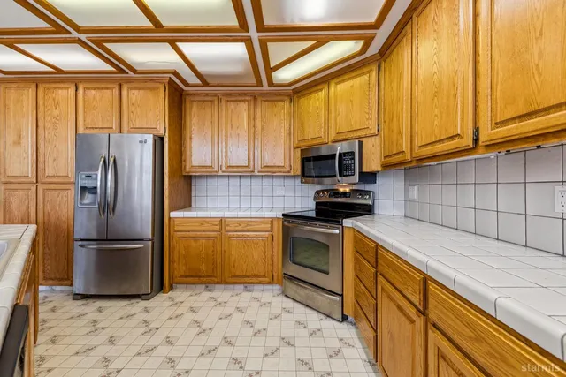 a kitchen with granite countertop a refrigerator and a stove top oven