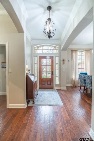 a living room with dining table wooden floor and a chandelier
