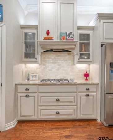 a kitchen with stainless steel appliances kitchen island granite countertop a refrigerator a sink dishwasher and white cabinets with wooden floor