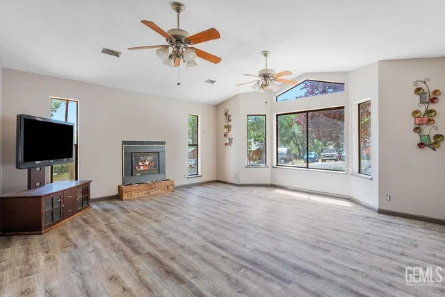 wooden floor in an empty room with a window and a flat screen tv