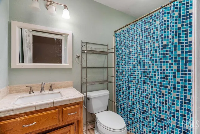 a bathroom with a granite countertop toilet a sink and a mirror
