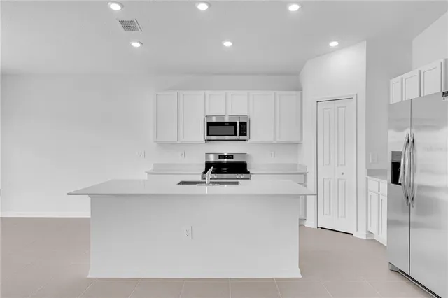 a kitchen with a sink a microwave a refrigerator and cabinets