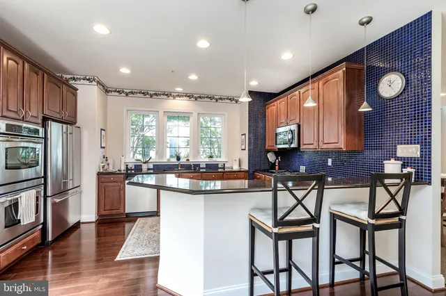 a kitchen with stainless steel appliances granite countertop table chairs and wooden floor