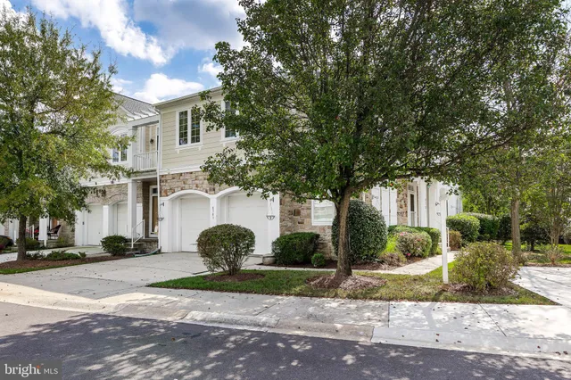 a view of a white house with a outdoor space and a tree
