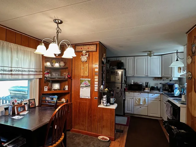 a kitchen with stainless steel appliances granite countertop a sink dishwasher a refrigerator a stove and a dining table with the kitchen view