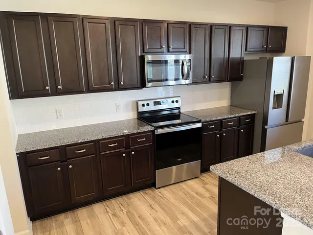 a kitchen with granite countertop wooden cabinets and stainless steel appliances