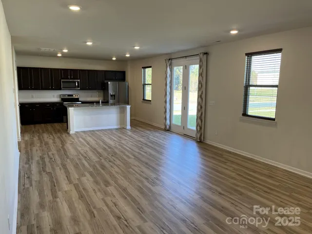 a view of kitchen with stainless steel appliances kitchen island wooden floors and living room view