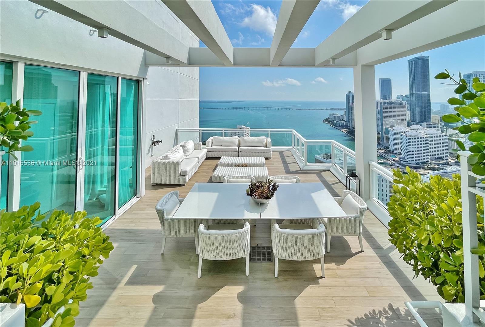 900 Brickell Key Boulevard, Unit PH4 Miami, FL 33131 - Photo 42 of 79 a view of a patio with table and chairs potted plants with floor to ceiling window