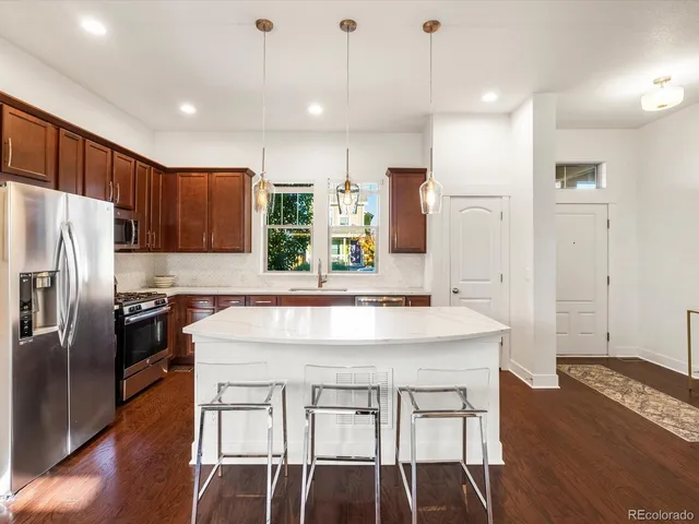 a kitchen with stainless steel appliances granite countertop a sink a stove a refrigerator a washer dryer and white cabinets