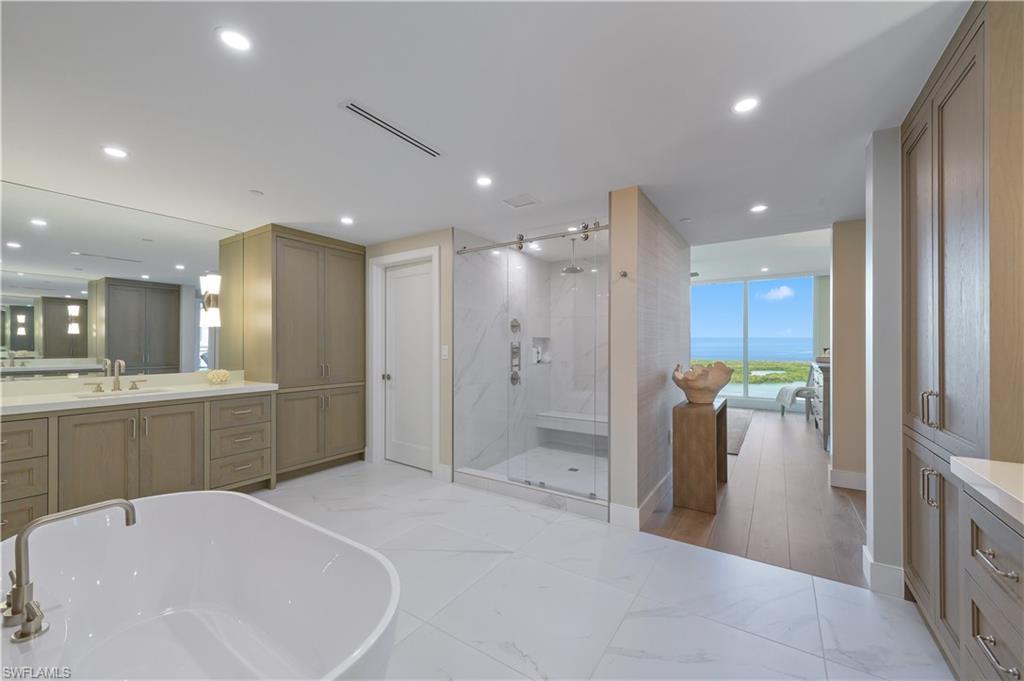 13945 Old Coast Road, Unit 1606 Naples, FL 34110 - Photo 14 of 35 a bathroom with a tub a sink and a large mirror