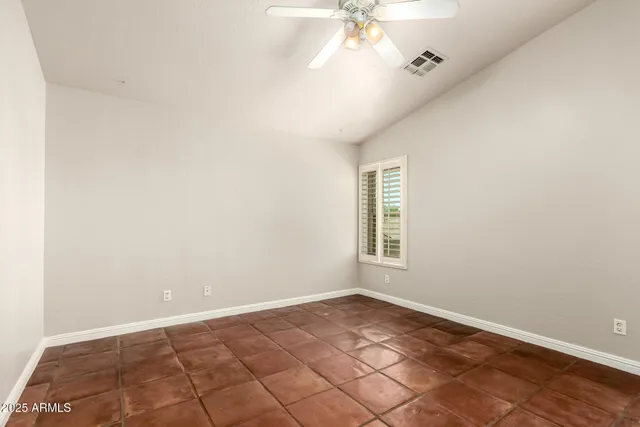 an empty room with a chandelier fan and windows