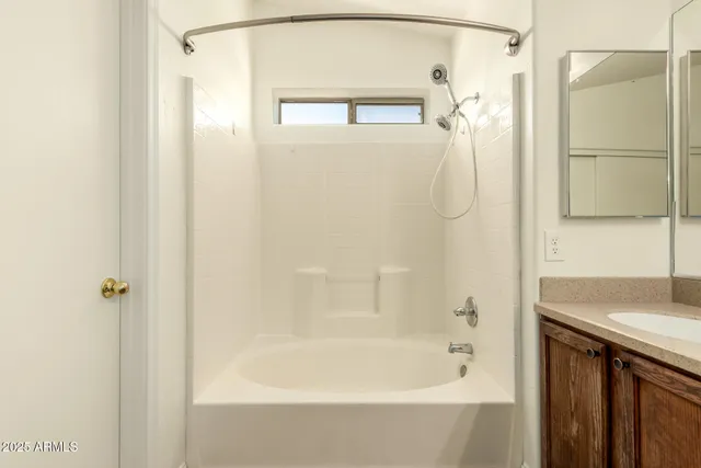 a bathroom with a granite countertop shower mirror and a bathtub